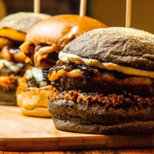Mouthwatering close-up of gourmet burgers on a wooden board, showcasing delicious textures and toppings.